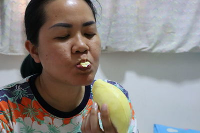 Close-up of woman eating fruit at home