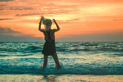 Woman standing in sea during sunset