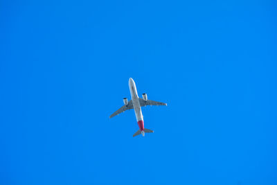 Low angle view of airplane against clear blue sky