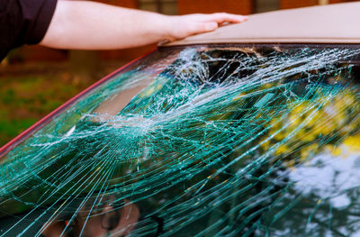 Cropped hand on car with broken windshield