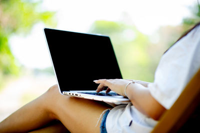 Midsection of woman using laptop at table