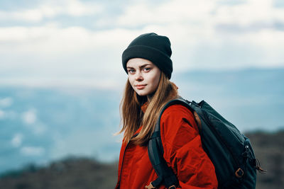 Portrait of beautiful young woman standing against sky