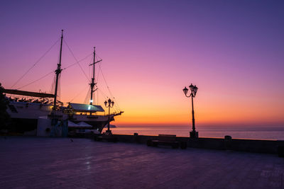 Sailboats moored at harbor against sky during sunset