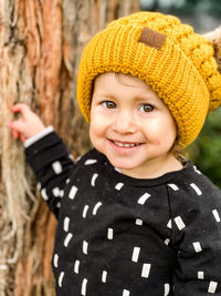 Portrait of smiling toddler with yellow beanie with puffy ears