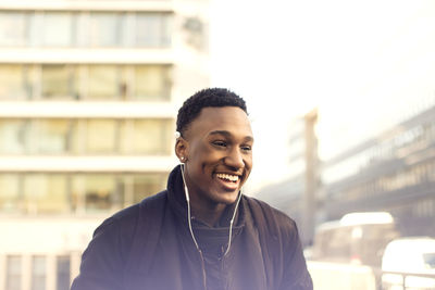 Portrait of smiling young man standing against building in city
