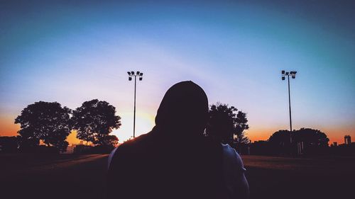 Rear view of silhouette man standing on street against sky