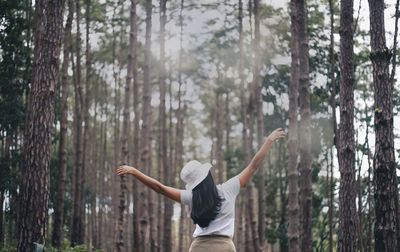 Rear view of woman standing in forest