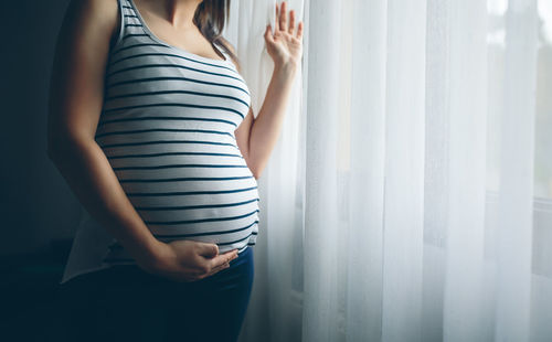 Midsection of woman standing against wall