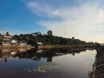 Reflection of trees and houses in lake against sky