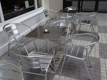 High angle view of empty chairs and tables at sidewalk cafe