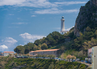 Lighthouse amidst buildings against sky