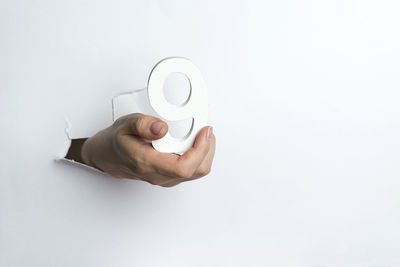 Close-up of hand holding cup against white background