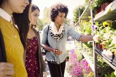 Female friends looking flowers at stall in market