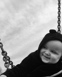 Close-up of happy baby boy looking away while sitting on swing