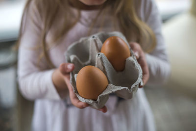 Midsection of girl holding egg carton