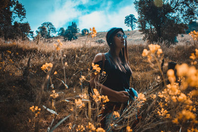 Woman standing by plants on field