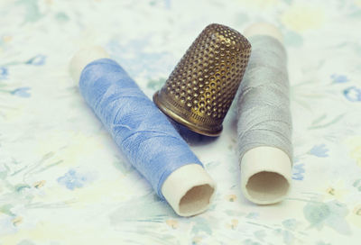 High angle view of thimble with threads on table