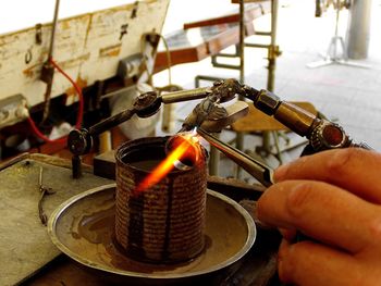 Cropped hand of jeweler making ring with flaming torch in workshop