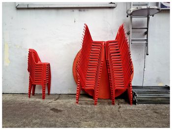 Stack of red chairs against wall