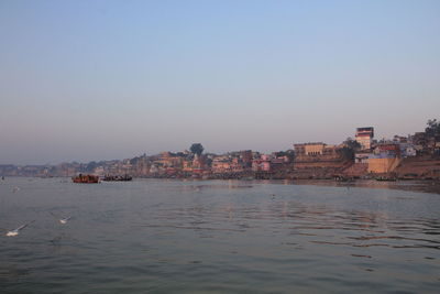 Buildings by sea against clear sky