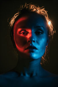 Close-up portrait of young woman against black background