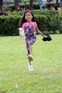 Full length portrait of smiling girl standing on grass