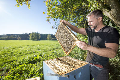 Man holding honeycombs against trees