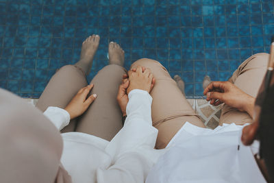 Low section of couple holding hands while relaxing in swimming pool