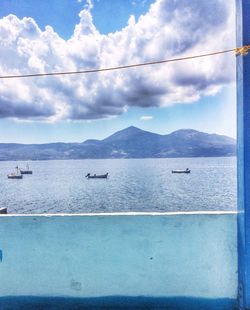 Boats in sea against cloudy sky