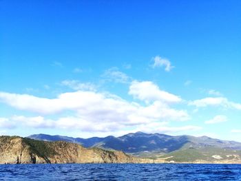 Scenic view of sea and mountains against blue sky