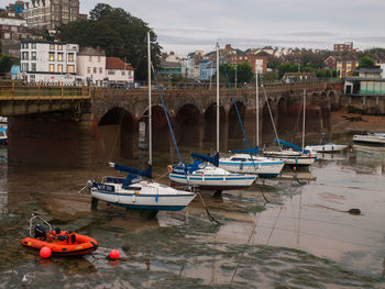 Boats moored on river against buildings in city