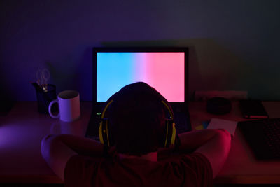 Rear view of man sitting on table at home