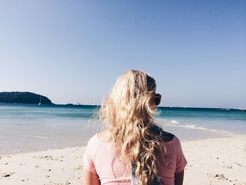 Rear view of friends at beach against clear sky