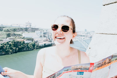 Portrait of young woman wearing sunglasses while standing against sky