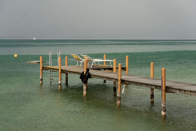 Deck chairs on wooden pier over lake during summer rain