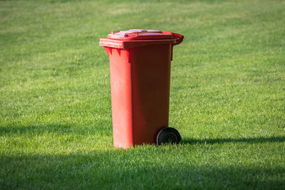 Close-up of red garbage bin on field