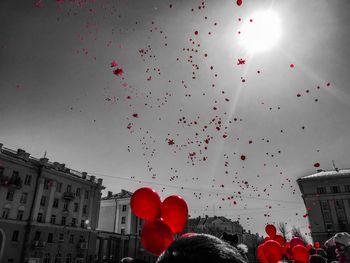 Low angle view of red balloons against sky in city