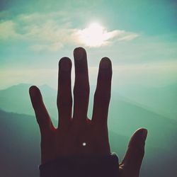 Close-up of human hand against sky