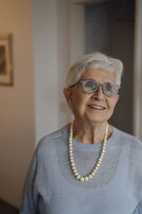 Smiling senior woman wearing eyeglasses standing at home