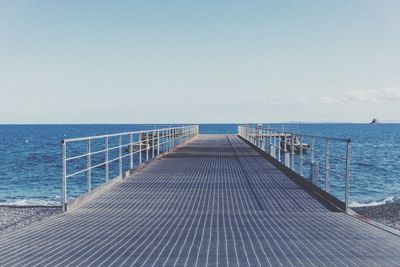 Empty pier over sea against clear sky