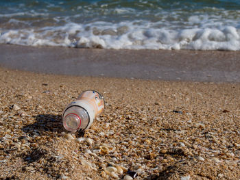 Close-up of bottle on sand at beach