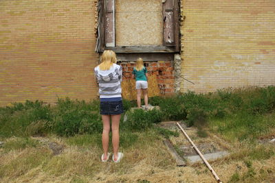 Full length of girls standing against old abandoned building