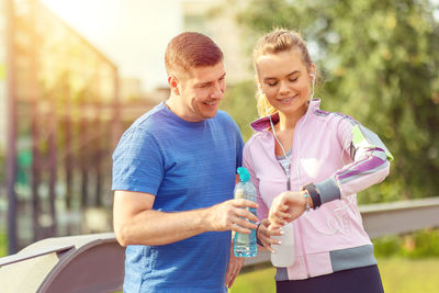 Happy sporty couple looking at heart rate monitor on smart watch after a run in park