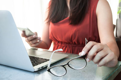 Midsection of woman using laptop on table