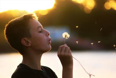 Side view of boy blowing dandelion 