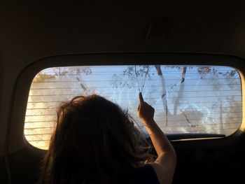 Rear view of woman looking through window