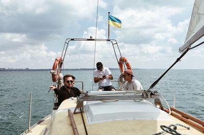 Friends in ship on sea against cloudy sky