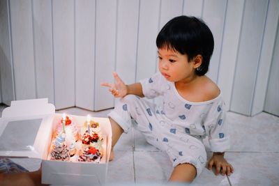 Portrait of cute baby boy sitting on floor at home