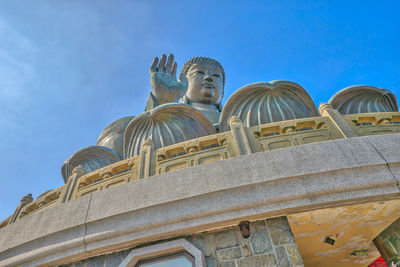 Low angle view of statue against blue sky and building