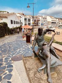 Statue on street against buildings in city